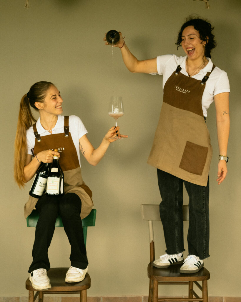 Due giovani cameriere con il grembiule del ristorante versano una bottiglia di vino