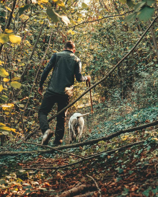 Giovane uomo e il suo cane in cerca di tartufi in un bosco